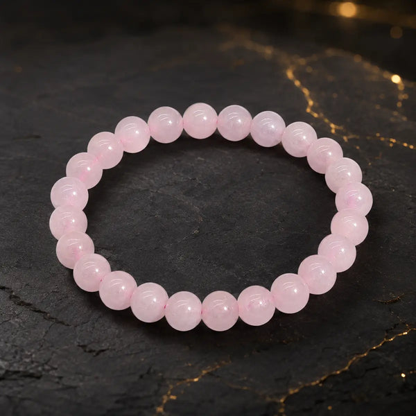 Bracelet en quartz rose à perles roses translucides sur fond sombre aux reflets dorés