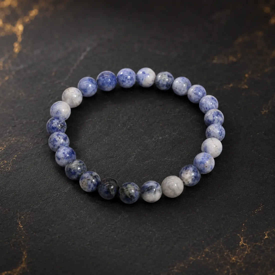 Bracelet en sodalite aux perles bleues et blanches marbrées sur fond sombre et doré