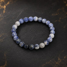 Bracelet en sodalite aux perles bleues et blanches marbrées sur fond sombre et doré