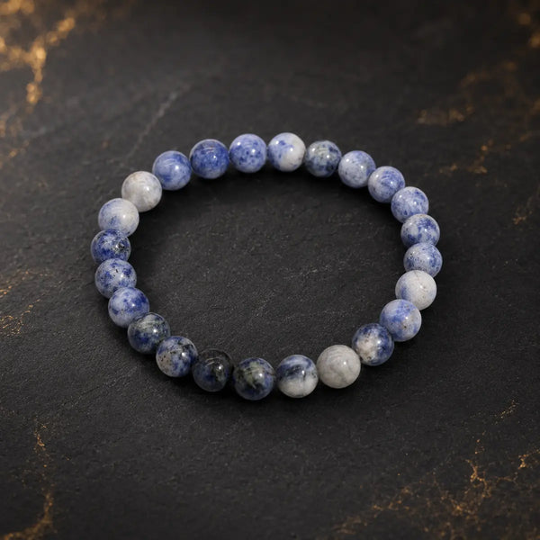 Bracelet en sodalite aux perles bleues et blanches marbrées sur fond sombre et doré